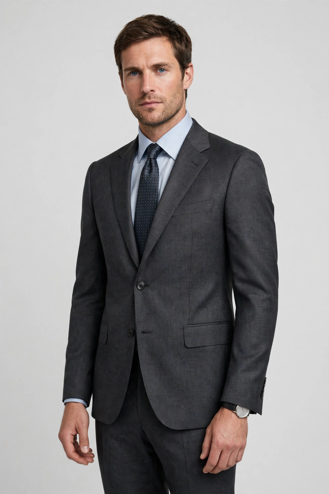 Man wearing a charcoal grey two-piece suit with a light blue shirt